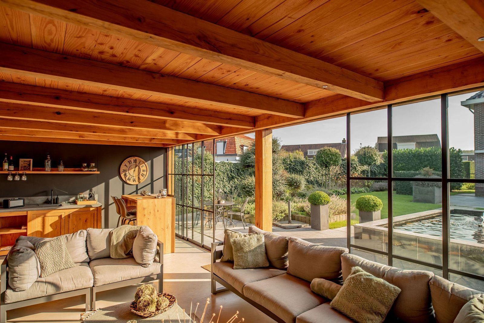 Garden room interior with a timber ceiling, sofas and wide glazing onto the garden