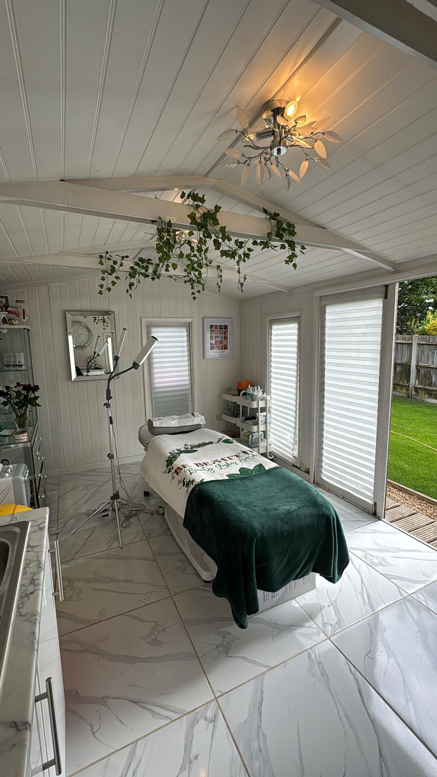 Beauty studio garden room with a treatment bed and hanging plants