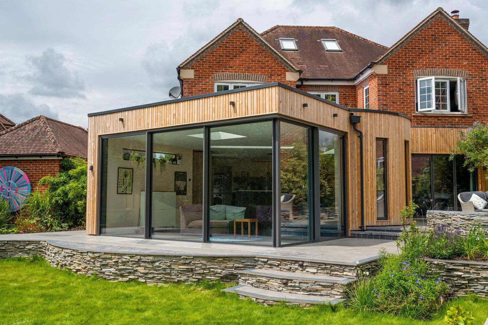 Contemporary glazed extension on a brick house, compared with a garden room