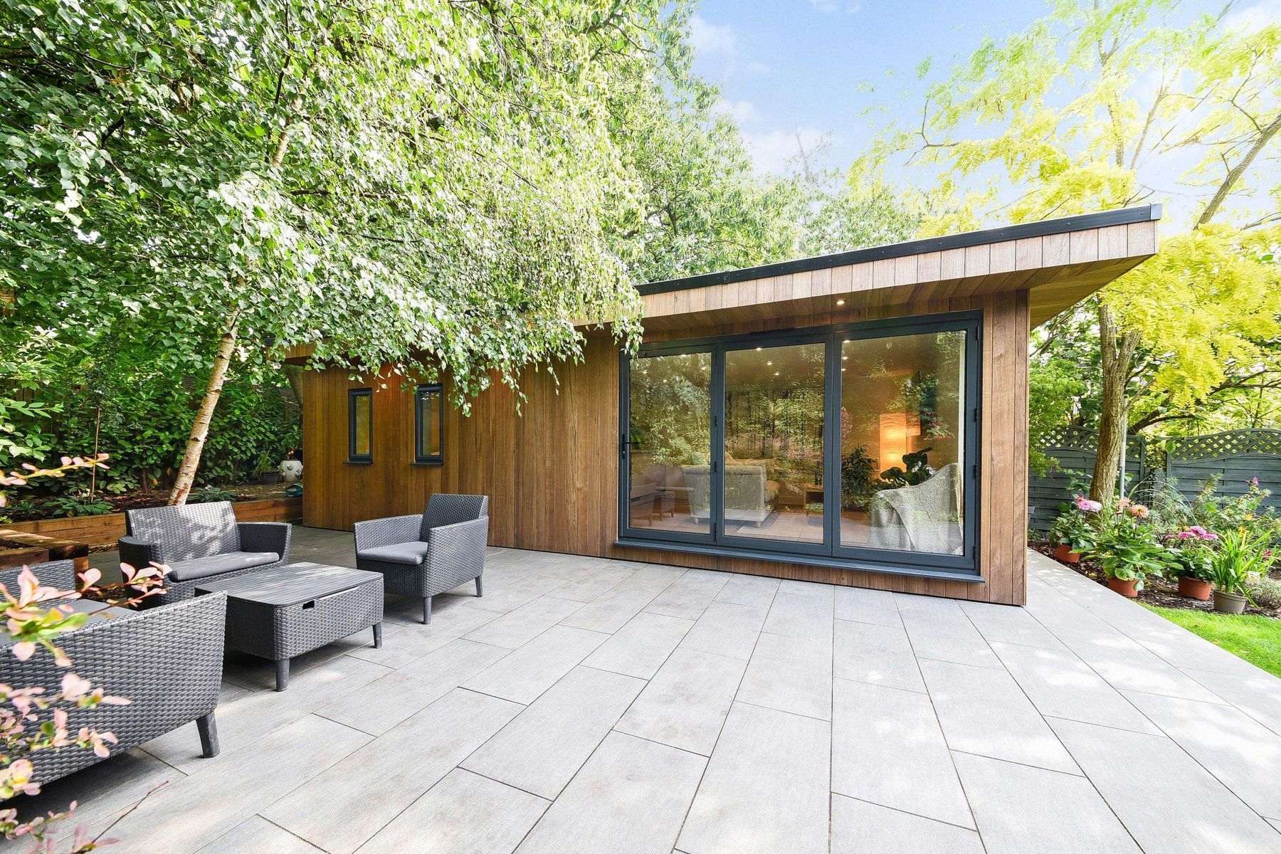 Contemporary timber garden room with sliding glass doors and a paved terrace
